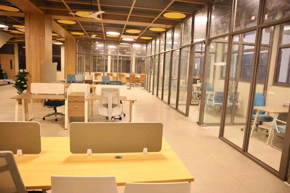 A run of glass-partitioned cabins beside an open desk floor