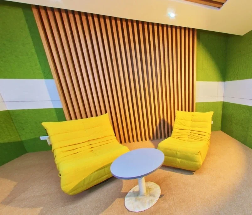 A studio pod: two lounge chairs and a low table against a slatted timber wall