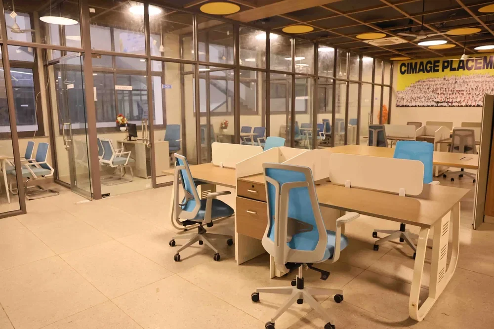 Desk clusters with mesh task chairs and screen dividers, glass cabins behind